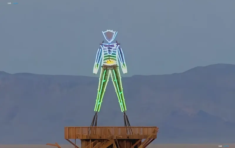 Leuchtende Neon-Figur eines Menschen auf einer Holzplattform — Kunstinstallation von Burning Man 2026 in der Nevada-Wüste