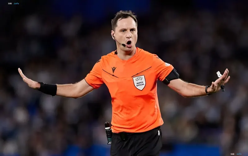 Schiedsrichter Serhij Balakin in orangefarbener UEFA Match Official-Kleidung, der bei einem Champions-League-Spiel pfeift