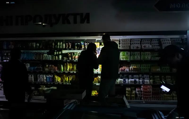 Shoppers pick products on lit supermarket shelves during a blackout in Kyiv