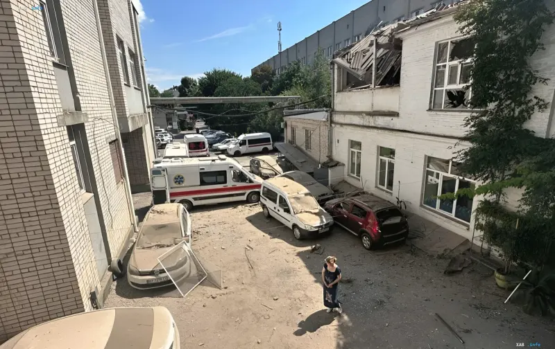 Damaged medical facility building in Ukraine after a Russian strike: destroyed roof, shattered windows and parked ambulances in the courtyard