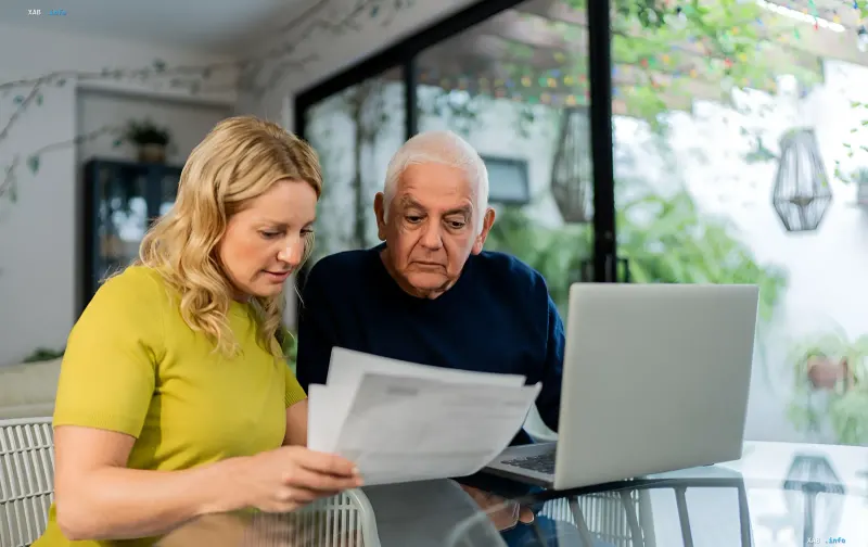 Senior man and woman reviewing documents and a laptop: debt collection and protected minimum income