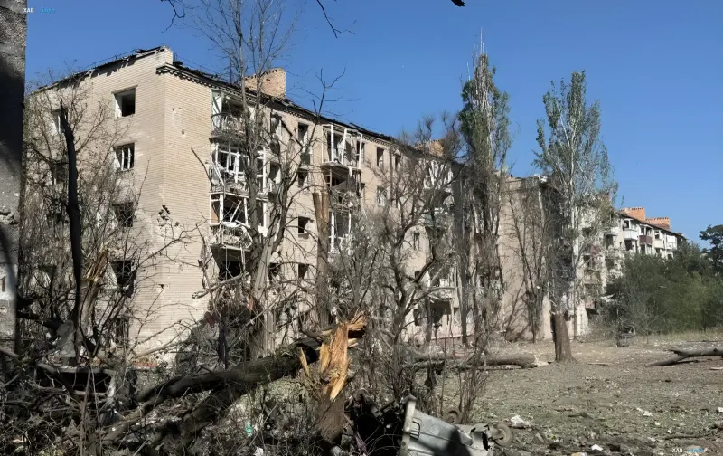 Damaged multi-storey residential building in Kramatorsk after a strike: shattered windows, destroyed balconies and broken trees in the courtyard