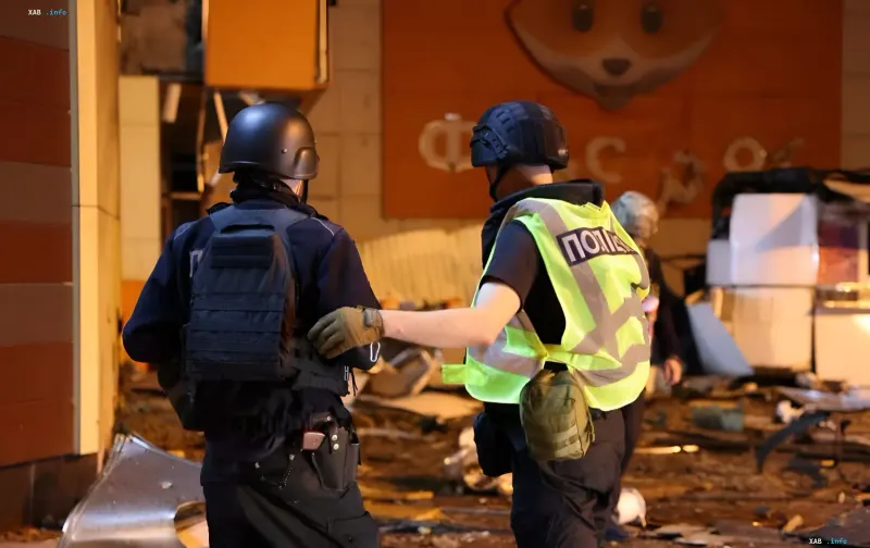 Police and rescue workers inspect the damage after a drone strike on a shopping center in Sumy