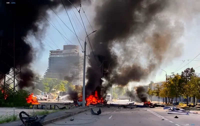 Folgen des Angriffs auf die Oleina-Fabrik in Dnipro: brennende Fahrzeuge, dicker schwarzer Rauch und Zerstörung auf einer Straße in der Stadtmitte