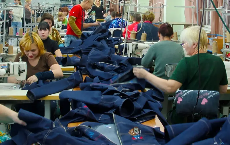 Näherei-Werkstatt der Gloria Jeans-Fabrik: Arbeiter an industriellen Nähmaschinen bearbeiten Denim-Stoff, bevor die Produktion nach Asien verlegt wird