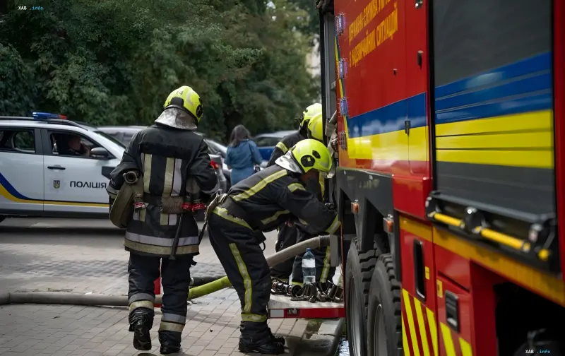Firefighters in protective gear prepare a hose on a fire truck after drone attack on office building in Kyiv's Podilskyi district