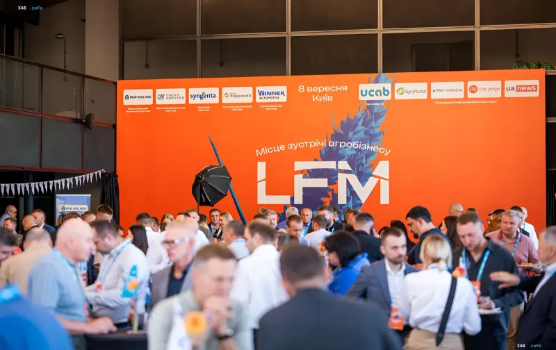 Учасники конференції LFM на нетворкінгу перед помаранчевим банером із логотипом LFM і написом «Місце зустрічі агробізнесу»