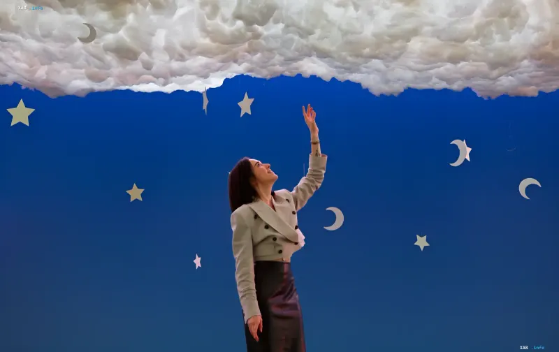 A visitor reaches toward a cloud installation with stars and moons at the 'That Day' exhibition in Kyiv