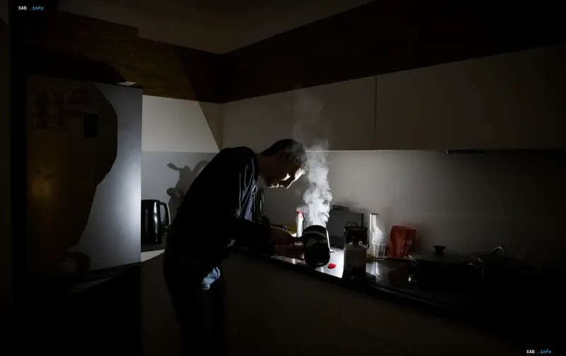 Mann kocht in einer dunklen Küche nach einem Stromausfall in Mykolaiw
