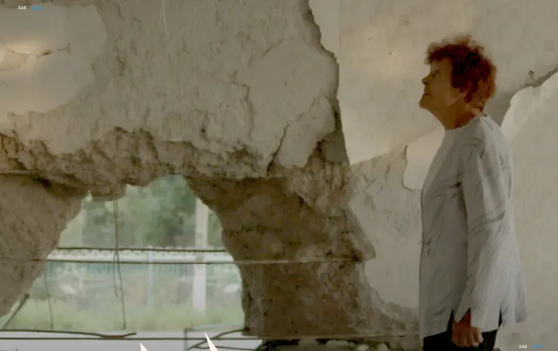 A woman by a damaged wall in a frame from the documentary 'Traces', submitted by Ukraine for the 2027 Oscars