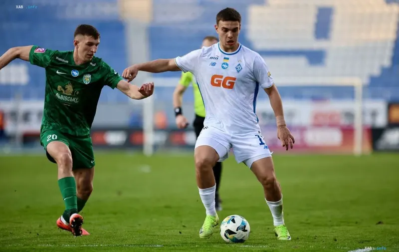 UPL-Spiel: Ein Dynamo-Spieler im weißen Trikot mit GG-Logo kontrolliert den Ball unter Druck eines Veres-Spielers im grünen Trikot während der ukrainischen Meisterschaft