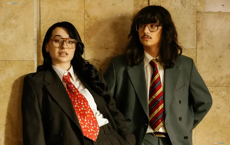 Musicians SadSvit and FIINKA in formal suits and retro glasses against a stone wall