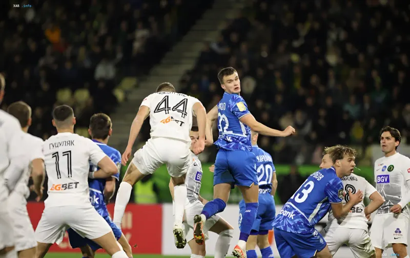 Footballers compete for an aerial ball during a Ukrainian Premier League match under floodlights