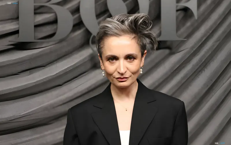 Veronica Leoni mit kurzem grauem Haar und Perlenohrringen in einem schwarzen Blazer bei einer Veranstaltung