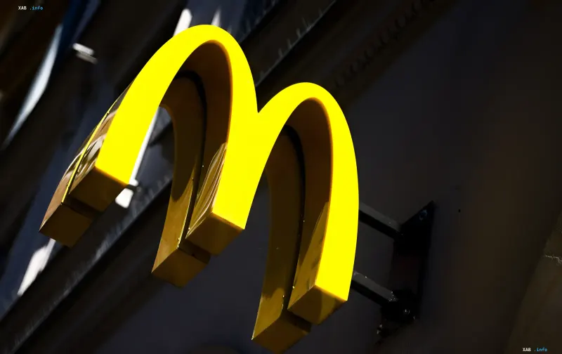 Золотий логотип McDonald's у вигляді величезної літери М на фасаді будівлі вночі