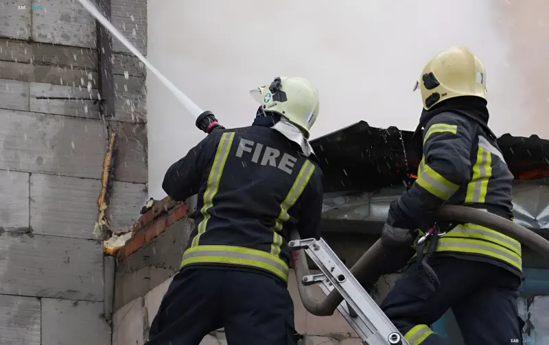 Firefighters extinguish a burning building following an enemy drone attack on infrastructure