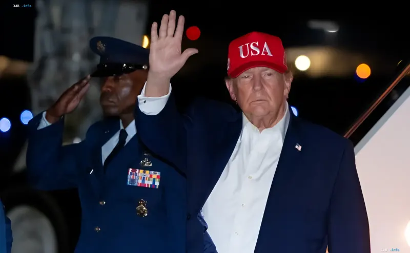 Дональд Трамп в красной кепке USA машет рукой рядом с военным в форме