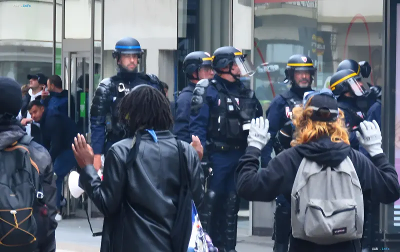 Французская полиция в защитном снаряжении перед протестующими с поднятыми руками во время беспорядков