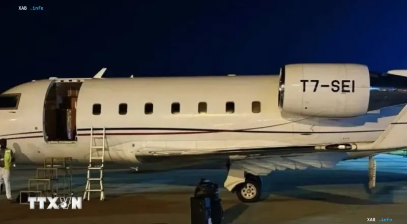 Weißes Privatflugzeug von Triton Aviation nachts auf dem Rollfeld eines Flughafens