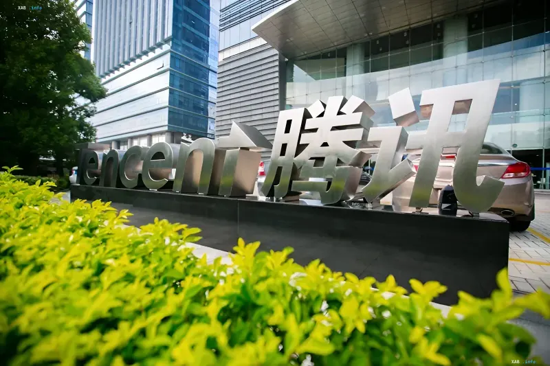 Корпоративный логотип Tencent на фоне современного небоскреба и зелени