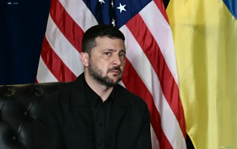 Президент Украины Владимир Зеленский сидит на фоне украинского и американского флагов