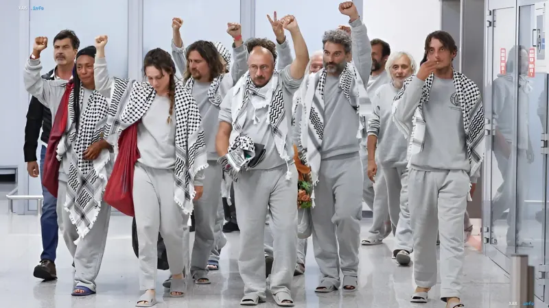 Eine Gruppe freigelassener Aktivisten in grauen Uniformen und Keffiyehs beim Gehen durch einen Flur