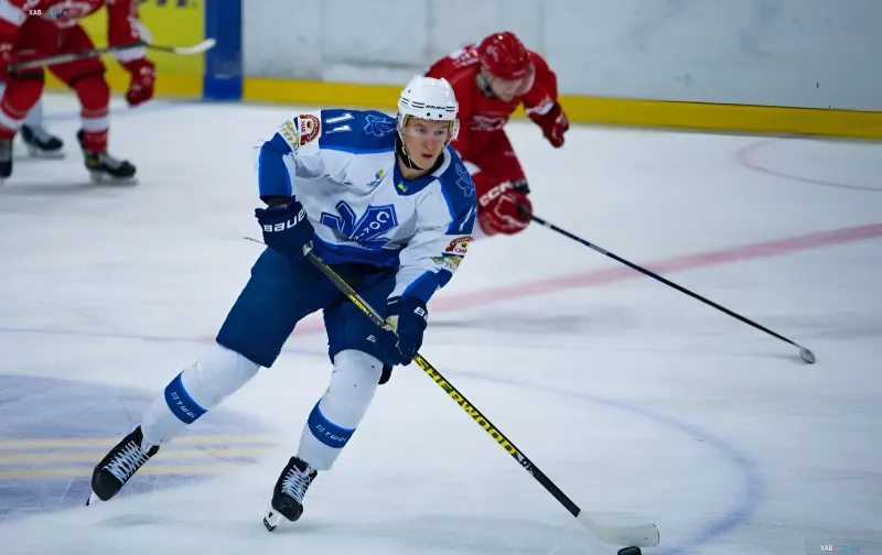 Ice hockey player in blue and white uniform stickhandling during a Continental Cup match