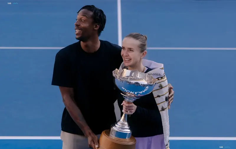 Elina Switolina und Gael Monfils halten einen Tennispokal auf einem blauen Platz