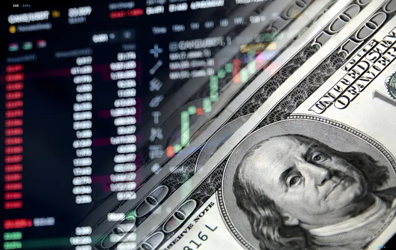 Trading charts on a monitor and a stack of US dollars with Franklin's portrait
