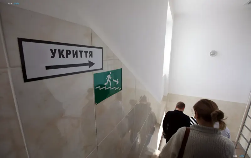 People walking down stairs toward a shelter following directional signs during an air raid alert in Kyiv
