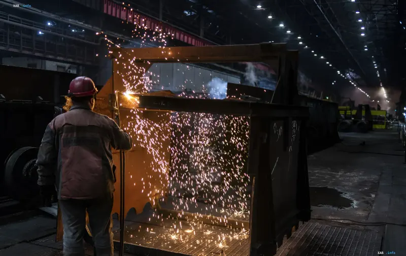 Ein Metallurg im Schutzhelm schweißt Metall mit Funkenflug in einem Werk in der Ukraine