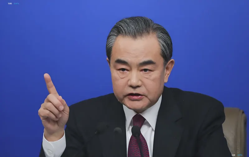 Chinese Foreign Minister Wang Yi gesturing during a briefing against a blue background