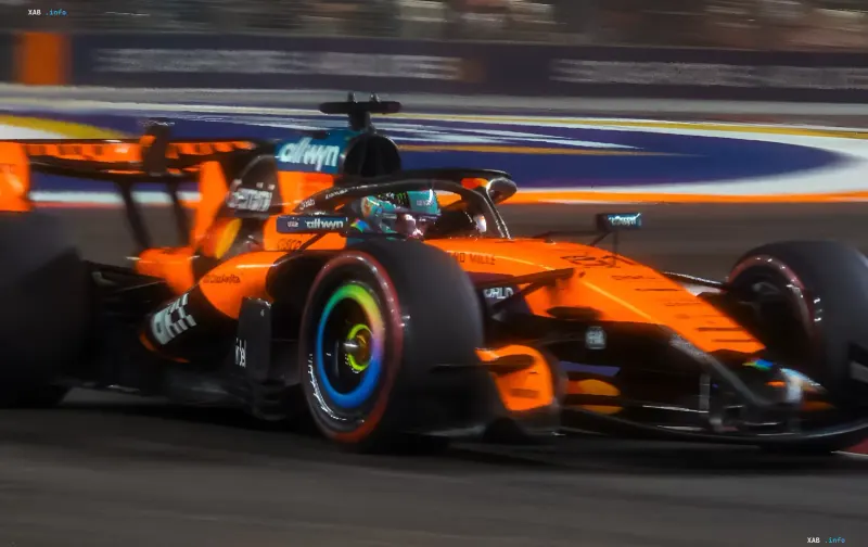Яскраво-помаранчевий гоночний болід команди McLaren на високій швидкості мчить нічною трасою Формули-1