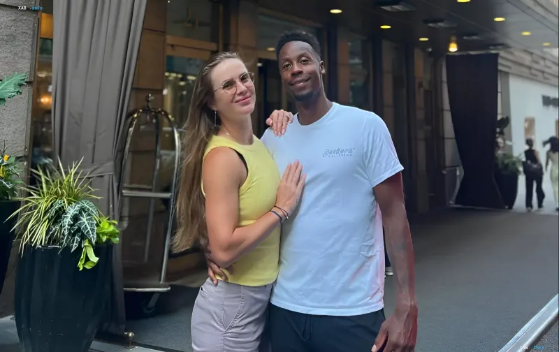 Gael Monfils and Elina Svitolina hugging outdoors near a hotel in casual clothing.