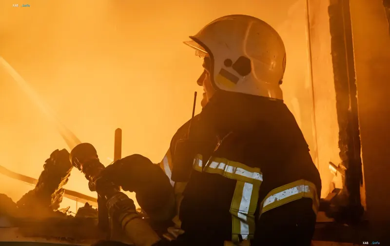 Firefighter in protective helmet extinguishing a massive fire at a destroyed enterprise