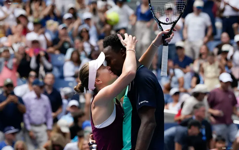 Elina Svitolina und Gael Monfils umarmen und küssen sich auf einem Tennisplatz vor Zuschauerrängen