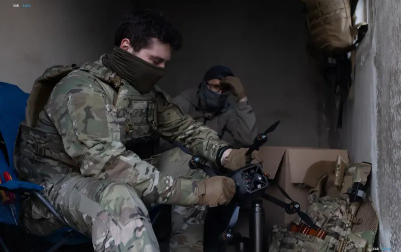 Soldiers in camouflage gear inside a shelter assembling and setting up an FPV drone for infrastructure protection