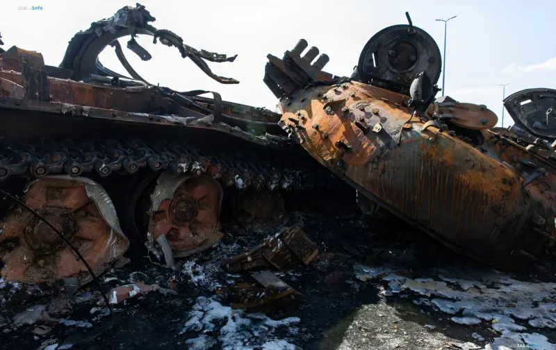 Burned Russian armored vehicles and a destroyed tank on a ruined road after battles