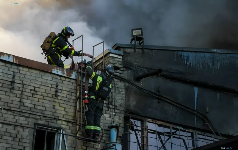 Firefighters extinguish a burning factory building, clearing the aftermath of a nighttime strike