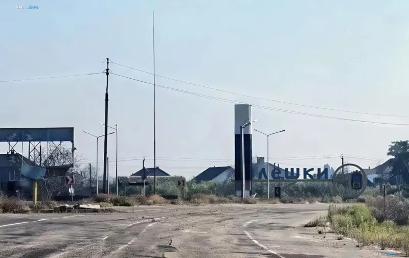 В'їзний знак з написом Олешки на тлі зруйнованої дороги та інфраструктури
