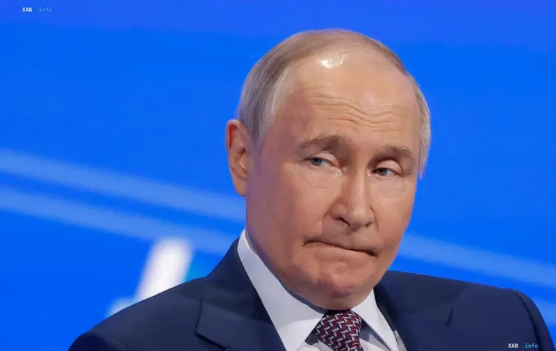 Президент России Владимир Путин выступает на фоне синего экрана во время мероприятия