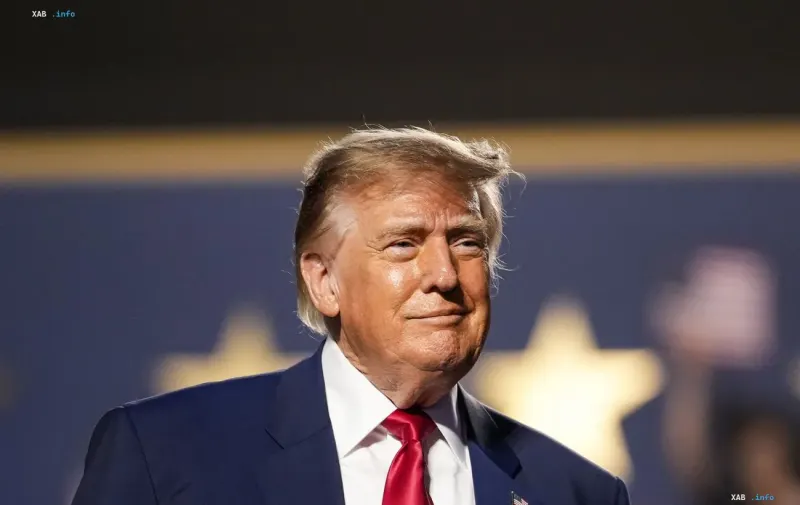 Президент США Дональд Трамп в темно-синем костюме с красным галстуком выступает перед аудиторией