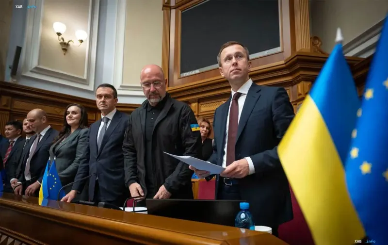 Representatives of the Ukrainian government in the parliament hall in front of Ukrainian and European flags.