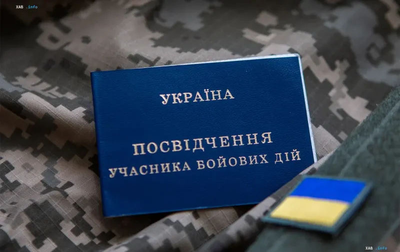 Синее удостоверение участника боевых действий Украины на камуфляжном фоне рядом с шевроном
