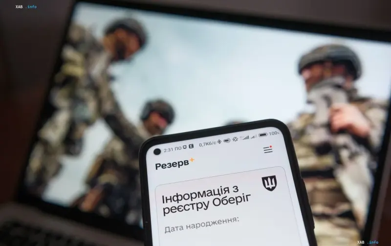 Смартфон з відкритим додатком Резерв+ на фоні ноутбука з військовими