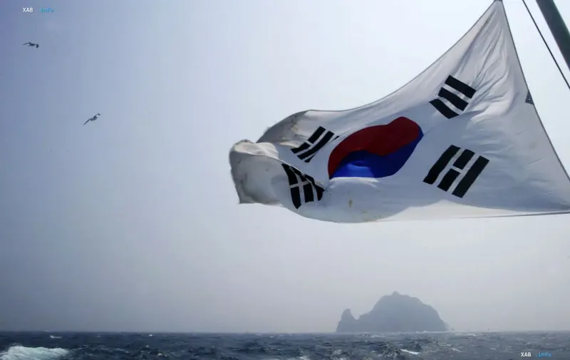 Südkoreanische Flagge weht im Wind vor einer Meereslandschaft und einer fernen Felseninsel