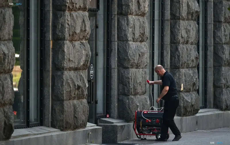 A man connects a portable generator on the street near a stone building in Kyiv