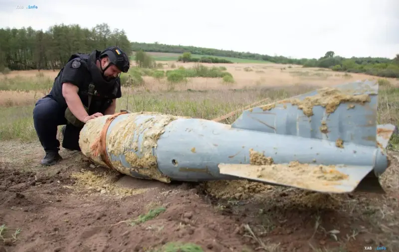 Ein Militärspezialist inspiziert die Trümmer einer großen gelenkten Fliegerbombe mit Heckflossen im Gelände