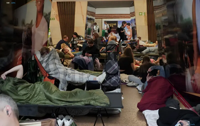 People on folding cots and sleeping bags in a Kyiv metro shelter during a night air raid alert