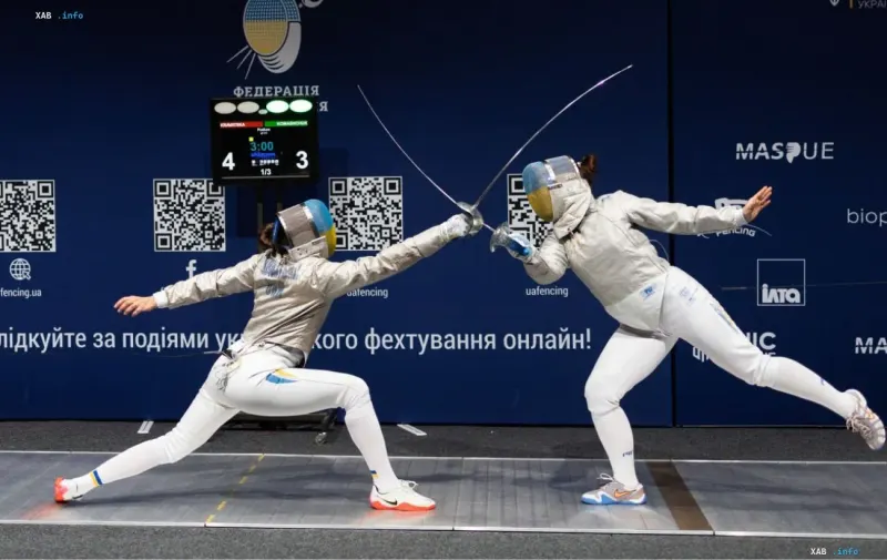 Две спортсменки-саблистки в защитных масках и фехтовальной экипировке соревнуются на дорожке во время Кубка Украины